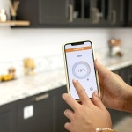 image représentant une main avec un telephone pour controler un chaffage en domotique dans une cuisine