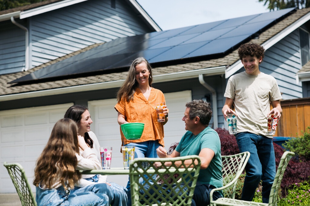 image d'une famille devant leurs maison avec des panneaux photovoltaique sur le toit