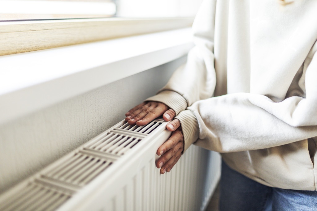 Femme qui se réchauffe les mains sur un radiateur