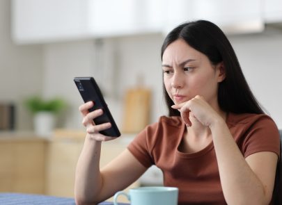 Femme dubitative devant son téléphone
