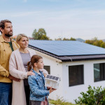 une famille en train de regarder vers l horizon avec une maison neuve en fond d'image