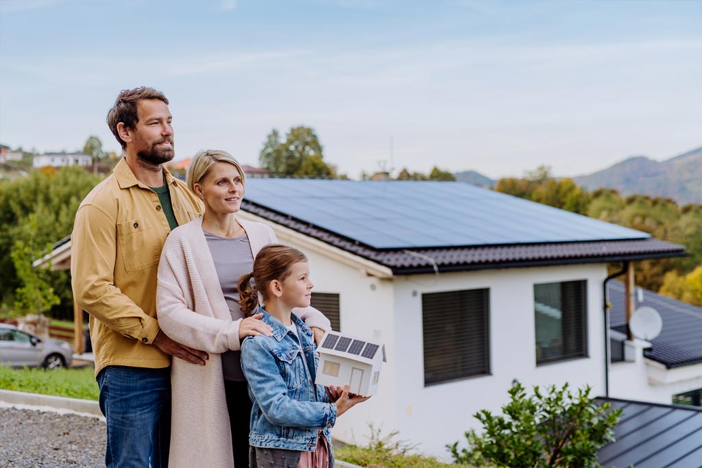 une famille en train de regarder vers l horizon avec une maison neuve en fond d'image