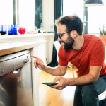 image d'un homme devant un lave vaisselle pour régler une plage horaire de programme