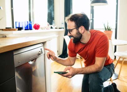 image d'un homme devant un lave vaisselle pour régler une plage horaire de programme