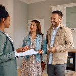 une femme devant un couple simulant une vente immobilière dans une cuisine