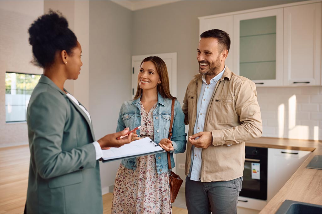une femme devant un couple simulant une vente immobilière dans une cuisine