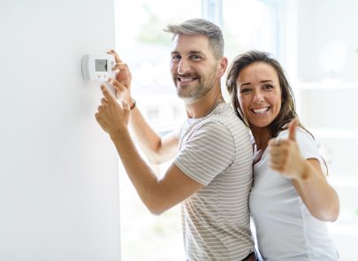 image d un couple devant un mur avec un boitier thermostatique