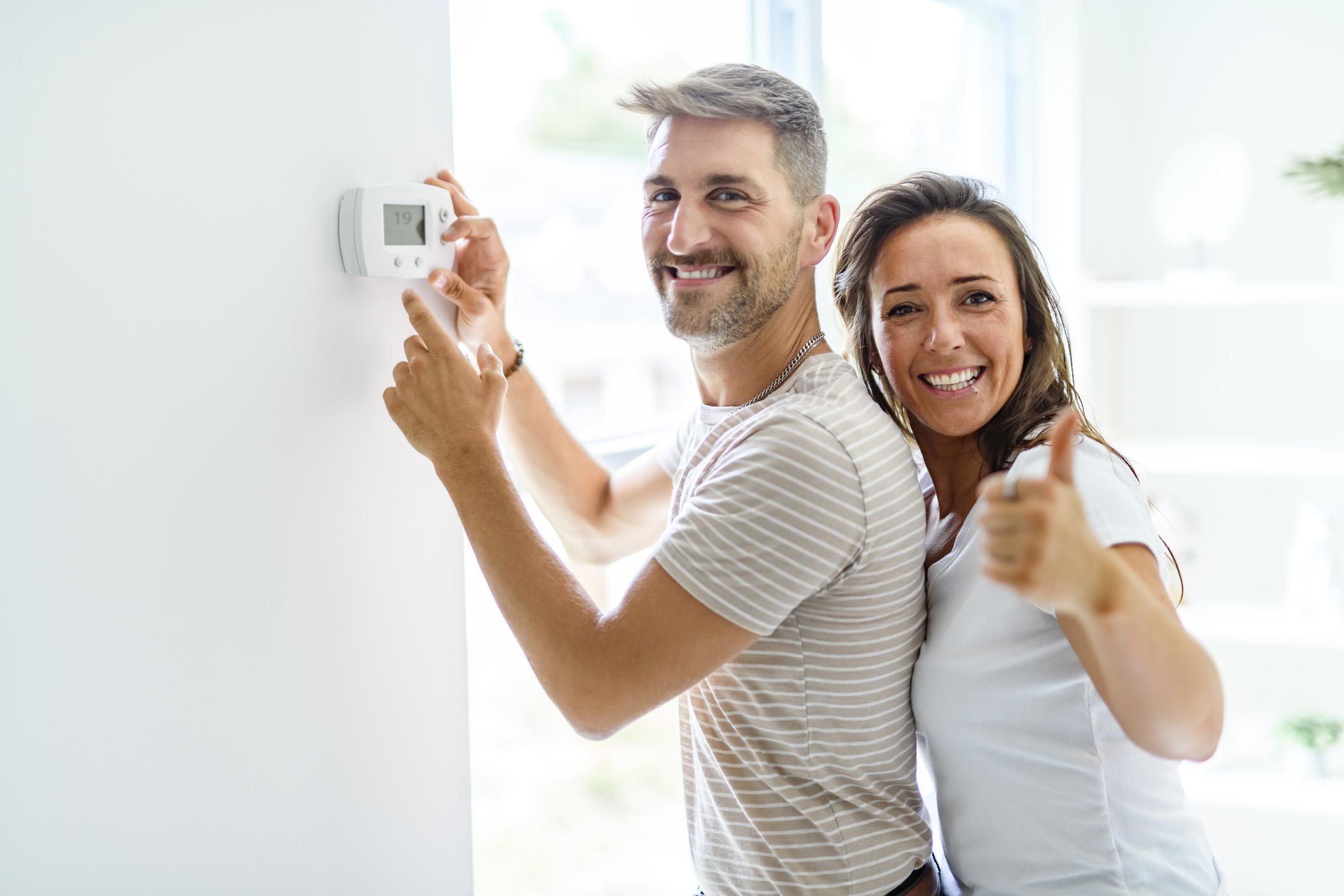 image d un couple devant un mur avec un boitier thermostatique