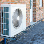 Pompe à chaleur, solution de chauffage durable pour les maisons modernes. Technologie de pompe à chaleur respectueuse de l'environnement installée sur la façade d'une maison en briques.
