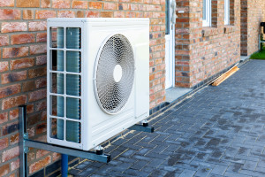 Pompe à chaleur, solution de chauffage durable pour les maisons modernes. Technologie de pompe à chaleur respectueuse de l'environnement installée sur la façade d'une maison en briques.