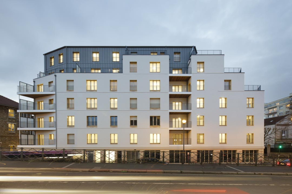 imge d'un batiment gris et blanc de logement collectif avec des lumières allumées
