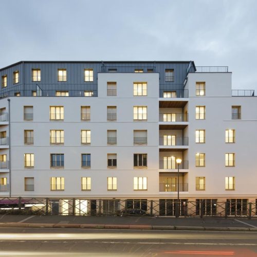 imge d'un batiment gris et blanc de logement collectif avec des lumières allumées