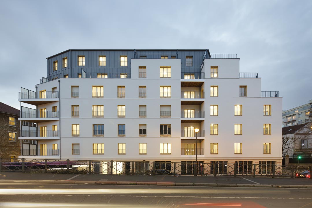 imge d'un batiment gris et blanc de logement collectif avec des lumières allumées